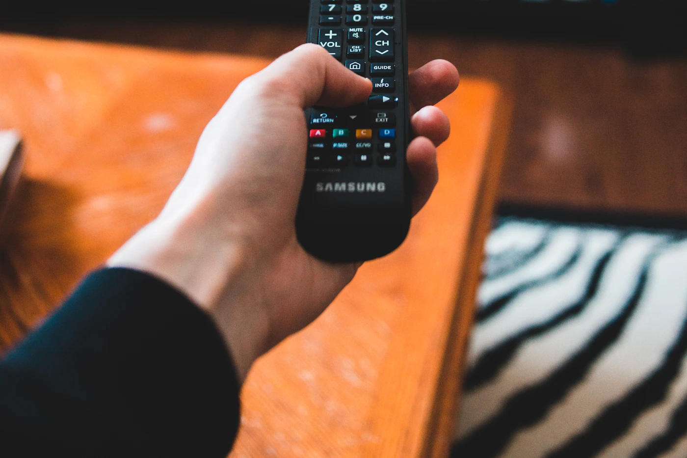 Close-up of a hand pointing a TV remote control