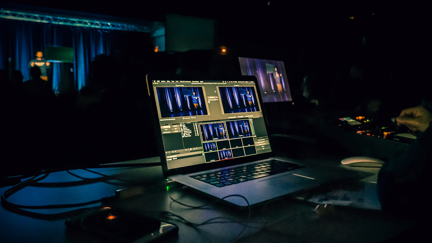Laptop on a desk in a dark room showing a video editing workspace
